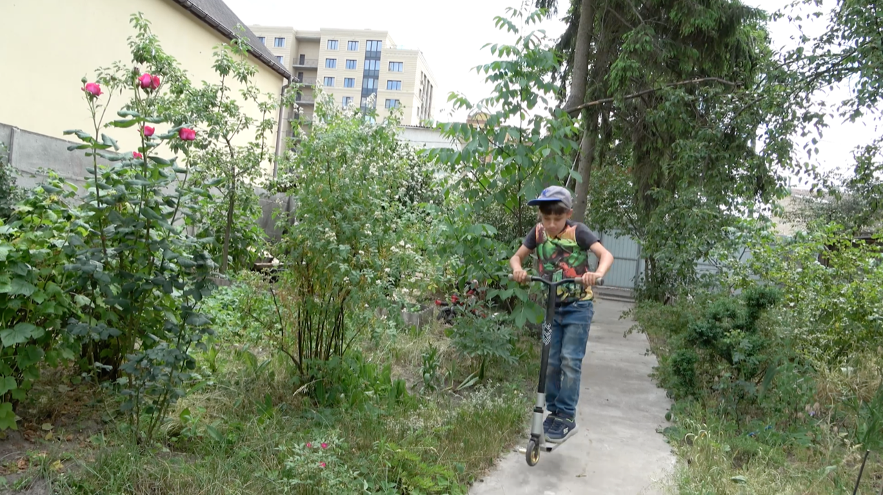 Ein Junge mit seinem Roller im Hinterhof ihres Hauses in Irpin, Ukraine.