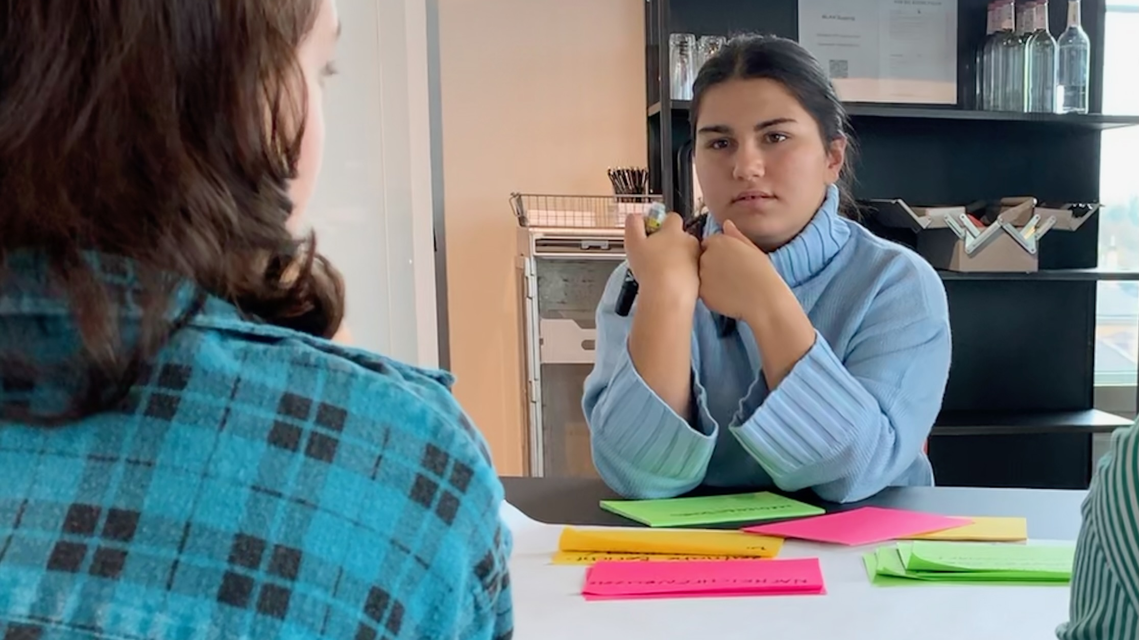 Zwei junge Frauen diskutieren ernsthaft miteinander. Auf dem Tisch liegen Post-it Zettel