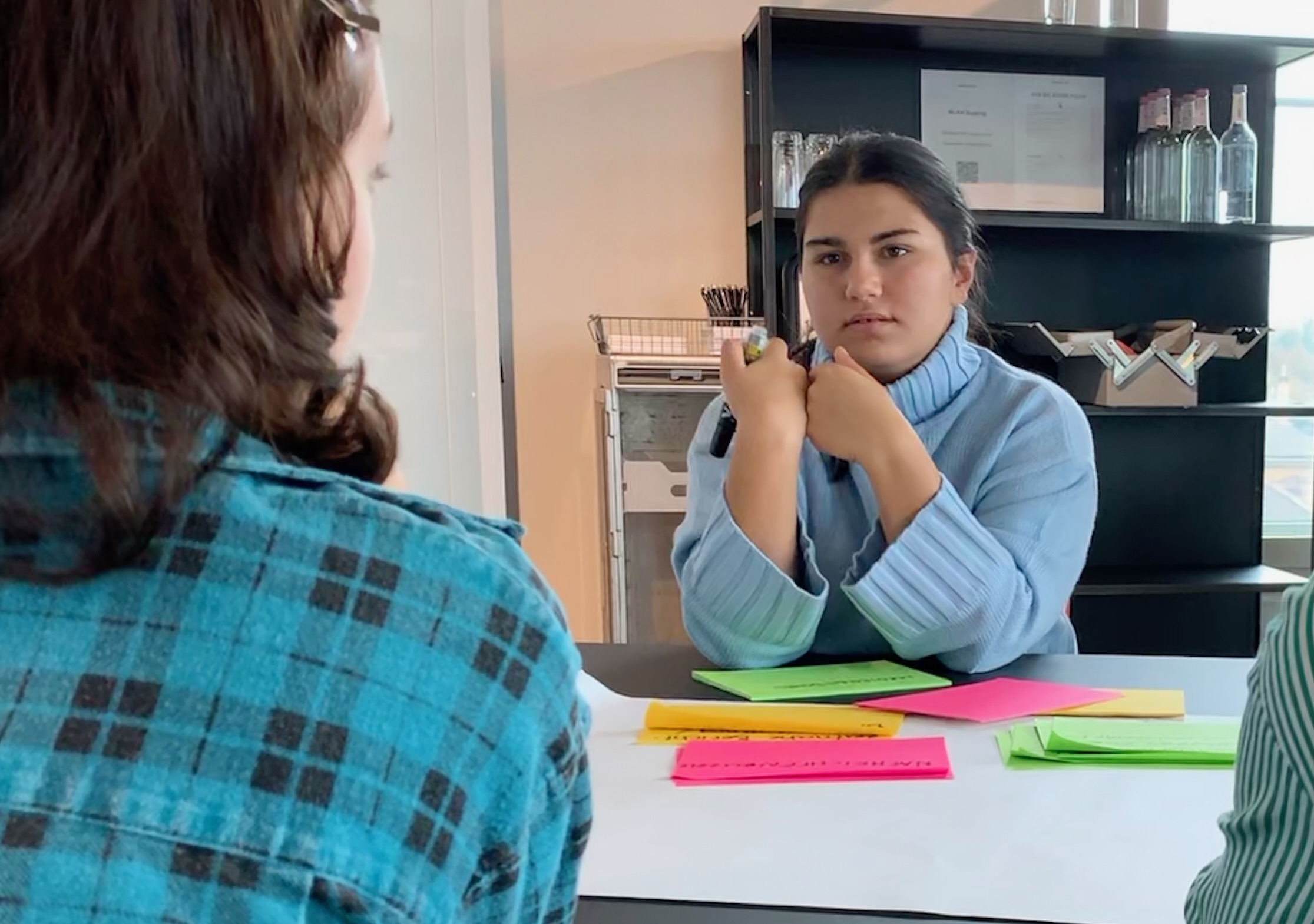 Zwei junge Frauen diskutieren ernsthaft miteinander. Auf dem Tisch liegen Post-it Zettel