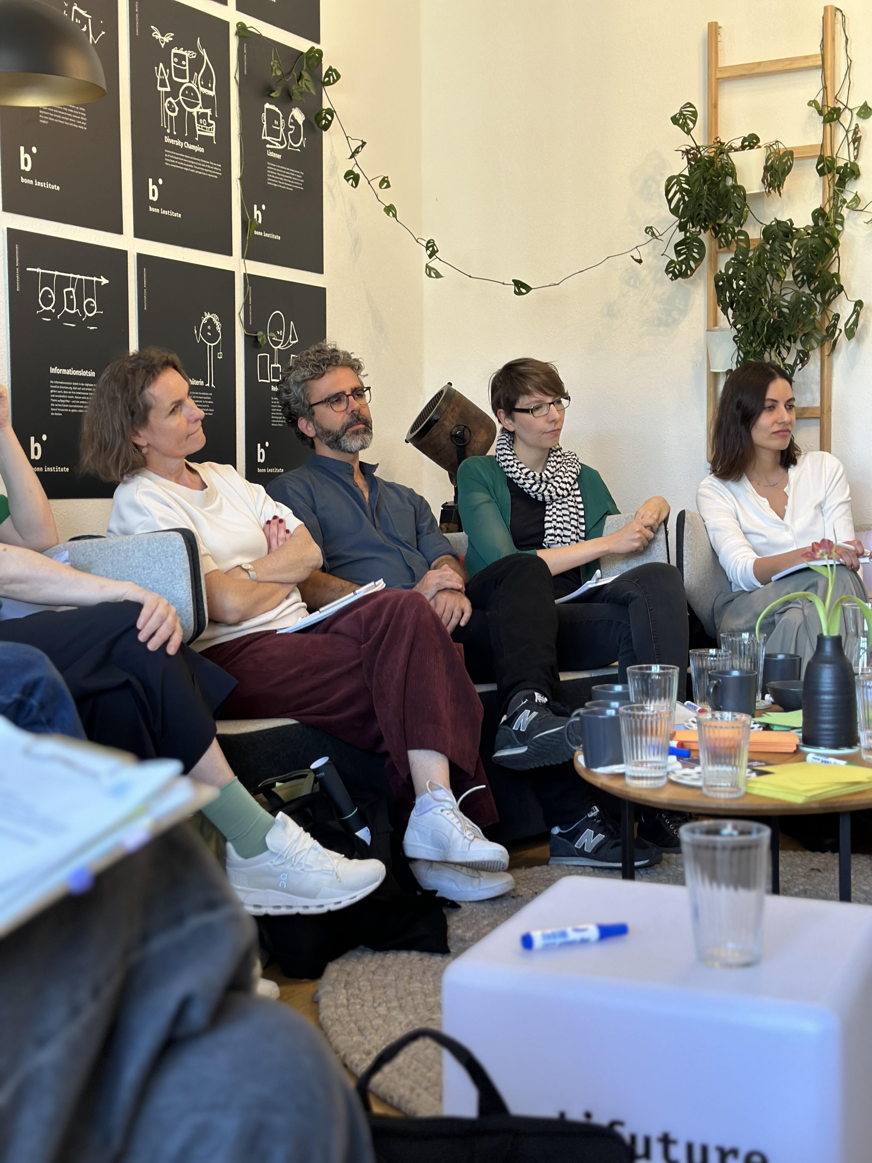 Four DW Fellows sit and listen to a presentation in the office of the Bonn Institute