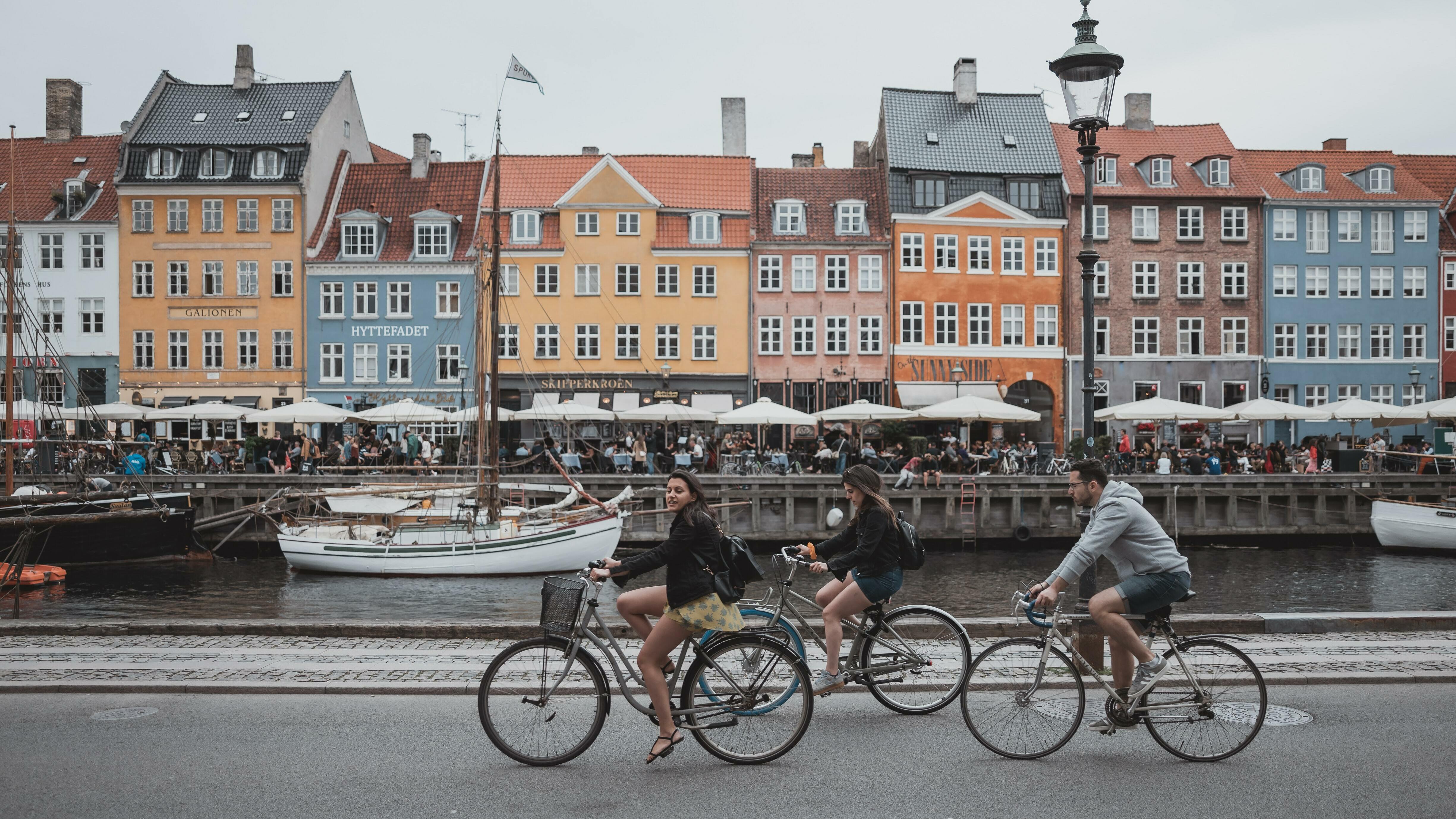 Drei Fahrradfahrer fahren am Nyhavn in Kopenhagen entlang
