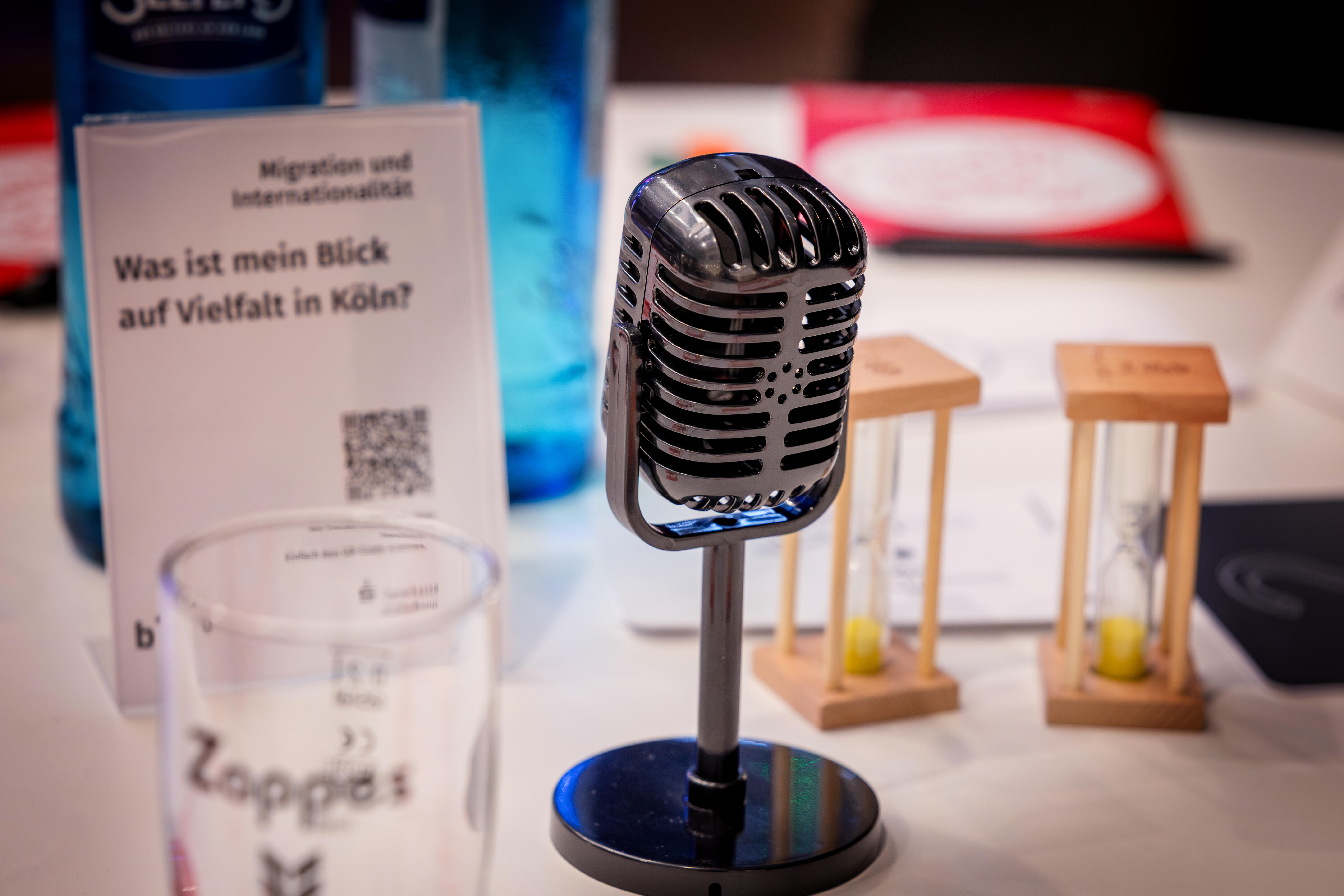 Verschiedene Spielmaterialien wie Mikrofon und Sanduhren auf einem Tisch.