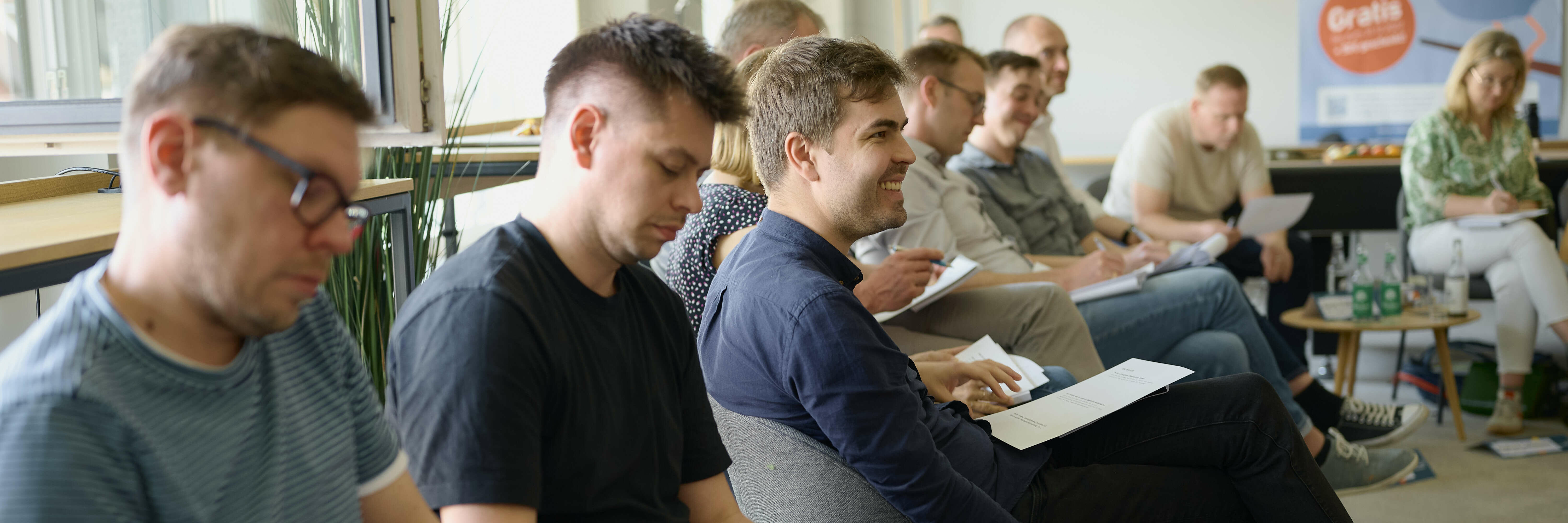 A group of individuals sit in chairs in a room during a learning event