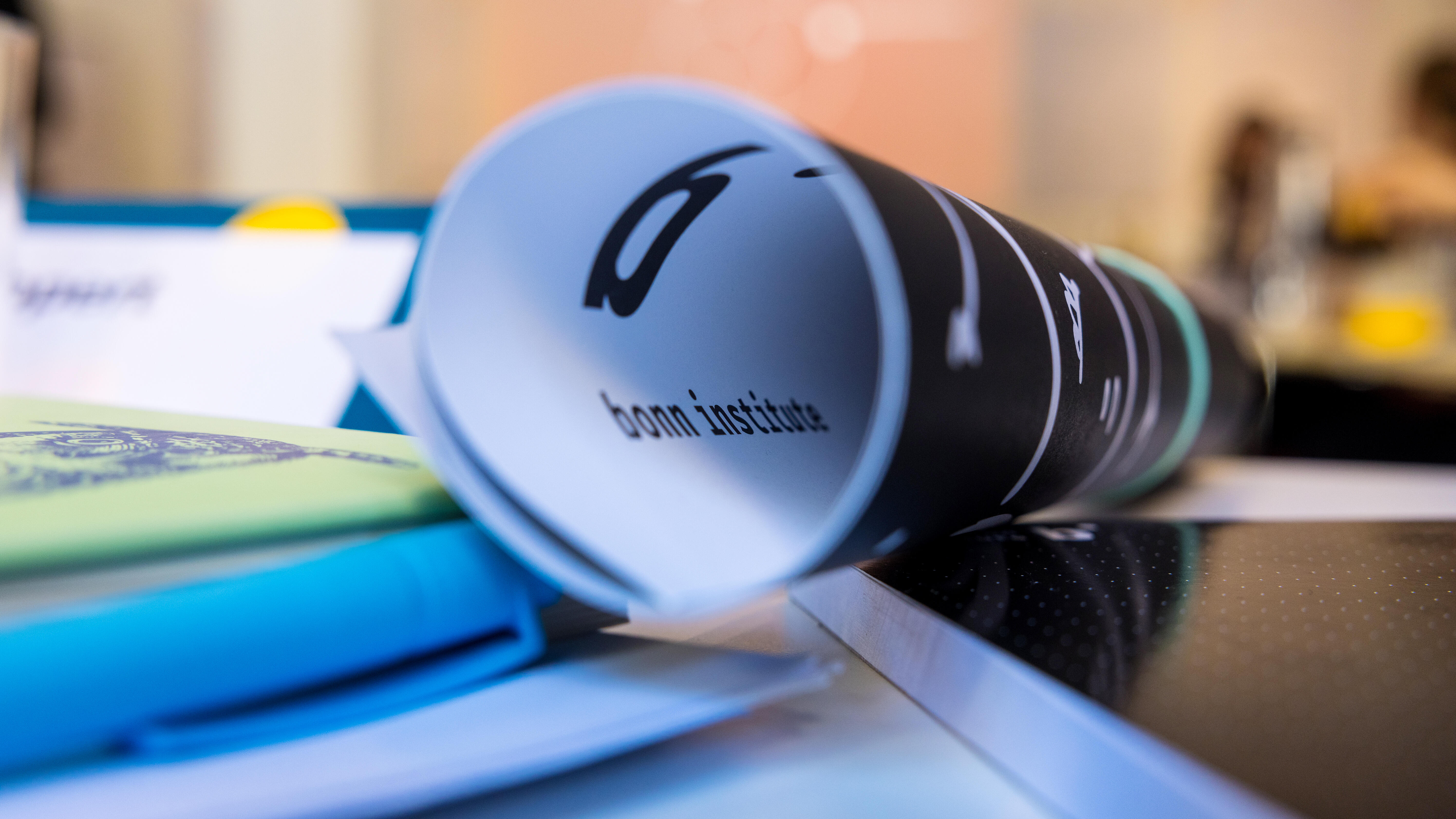 Ein zusammengerolltes Plakat des Bonn Institute liegt auf einem Schreibtisch