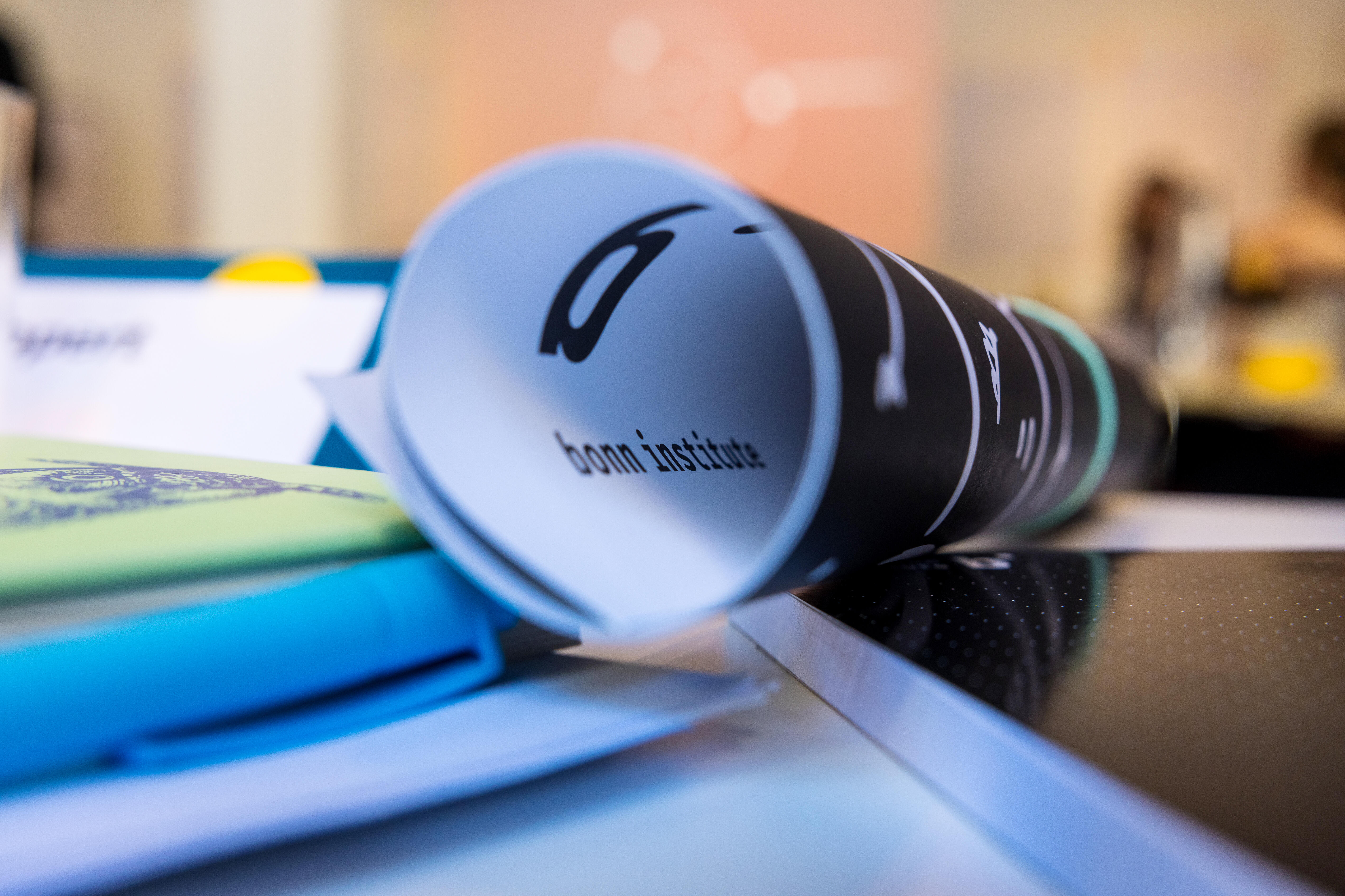 Ein zusammengerolltes Plakat des Bonn Institute liegt auf einem Schreibtisch